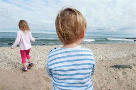 Preteen Girl Sitting On Beach With Barefeet Hugging Knees Stock