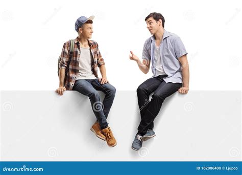 Deux Jeunes Hommes Assis Sur Un Panneau Et Parlant Photo Stock Image