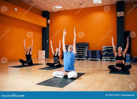 Grupo Con El Instructor Que Se Sienta En Actitud De La Yoga Imagen De