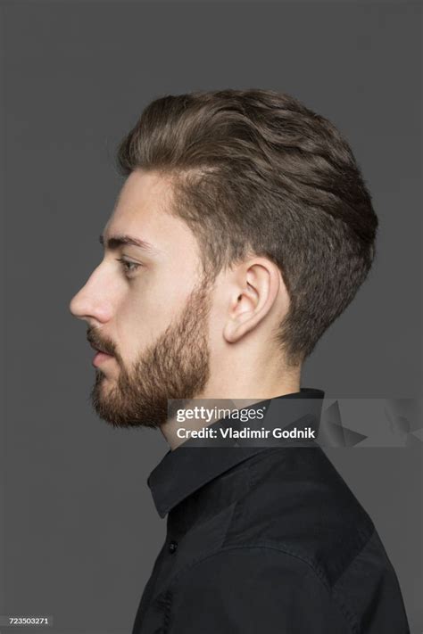 Side View Of Young Man Looking Away Against Gray Background High Res