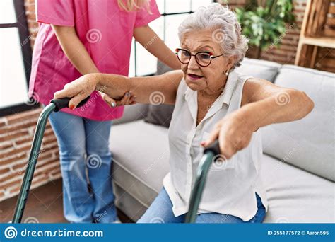 Senior Grey Haired Woman Patient Supported For Nurse And Walker At