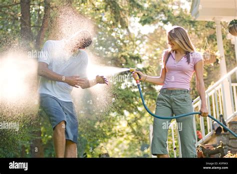 Teenage Girl Spraying Teenage Boy With Water Hose Stock Photo Alamy