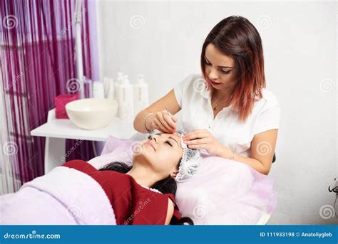 Beautiful Female Cosmetologist Giving Facial Treatment To A Brunette
