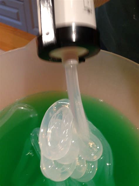 A Green Liquid Is Being Poured Into A White Bowl With A Black And