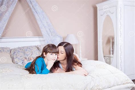 Mom Kissing Her Beautiful Daughter Happy Mother And Daughter Lay In Bed Having Fun Smiling And