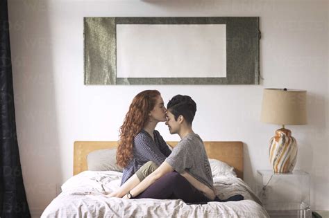 romantischer lesbischer kuss auf die stirn der freundin beim sitzen auf dem bett zu hause