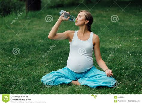 Pregnant Yoga Woman Drinking Water From A Bottle In The Lotus Position