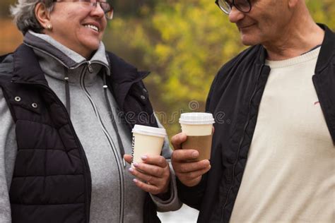 Happy Senior Couple Walking In Autumn Park And Drinking Coffee Elderly