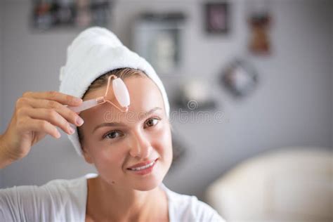 massage facial une belle femme se fait masser le visage en utilisant un rouleau facial jade pour