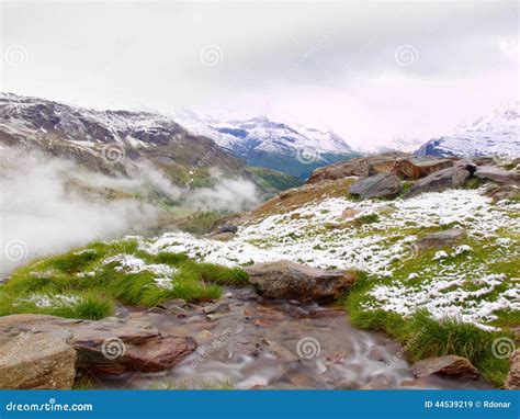 First Snow In Alps Touristic Region Fresh Green Meadow With Rapids