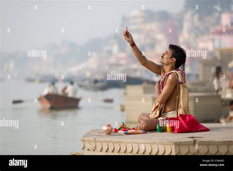 sadhu praying on the ghats lining the river ganges with a rowboat in the background varanasi