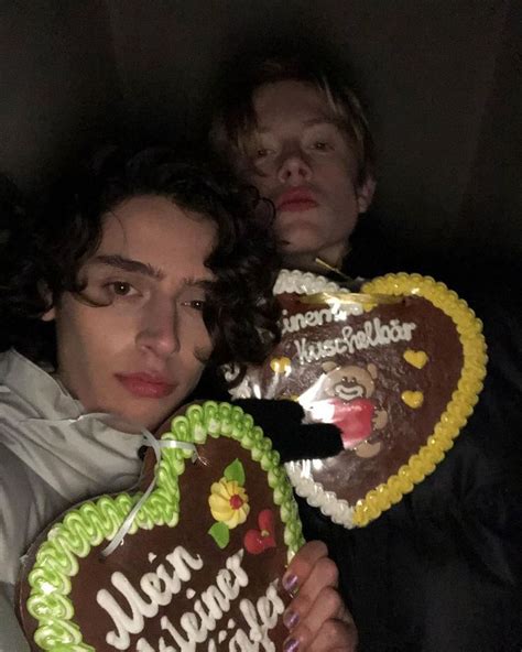 Two Young Men Are Holding Heart Shaped Cookies