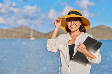 Premium Photo Portrait Of Happy Mature Woman In Straw Hat With Laptop On The Beach Copy Space