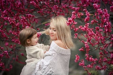 Madre Joven Con La Hija Adorable En Parque Con El árbol Del Flor Madre