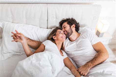 Happy Couple Is Lying In Bed Together Enjoying The Company Of Each