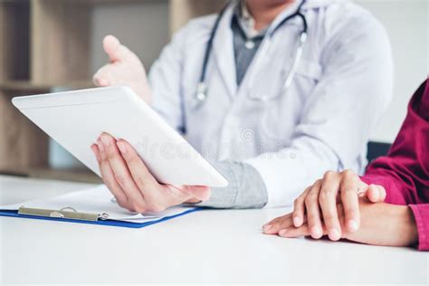 Doctor Consulting With Patient Presenting Results On Digital Tab Stock