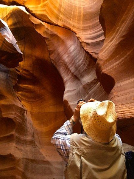 A Person Wearing A Hat Standing In The Middle Of A Canyon