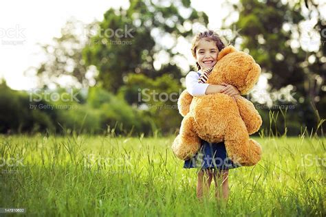 Gadis Kecil Yang Lucu Berdiri Di Rumput Memegang Boneka Beruang Foto
