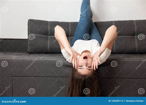 Young Beautiful Brunette Woman Lying On The Sofa Upside Down In Her