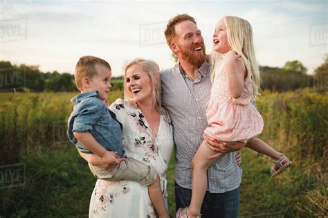 Smiling Parents Holding Children In Rural Area Stock Photo Dissolve