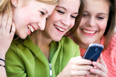 Three Female Friends Laughing And Looking At Cell Phone Stock Photo By Pikselstock