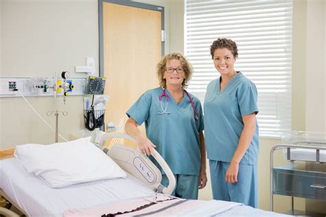 Nurses Standing Together By Bed In Hospital Room V Nsterpartiet