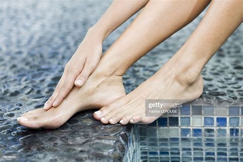 Woman Rubbing Her Foot At The Poolside Photo Getty Images