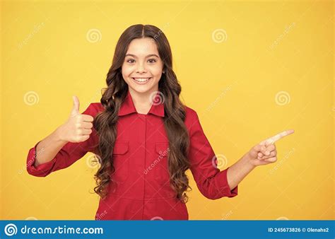 Cheerful Child Girl Pointing Finger On Copy Space With Thumb Up Gesture