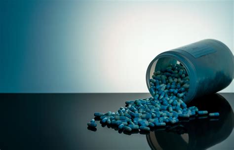 Blue And White Capsule Pill Spilled Out From White Plastic Bottle