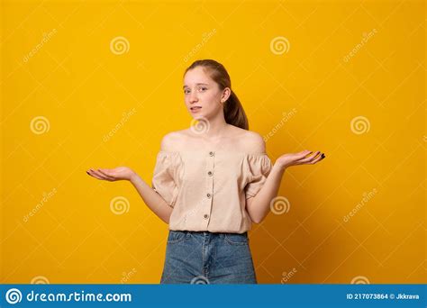 Puzzled Girl In A Gray Sweater Stands On A Pink Background Spreads Her