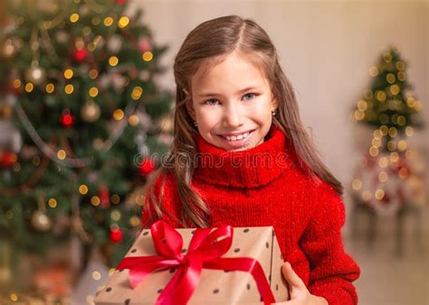 Cute Little Child Girl With Present T Box Near Christmas Tree At