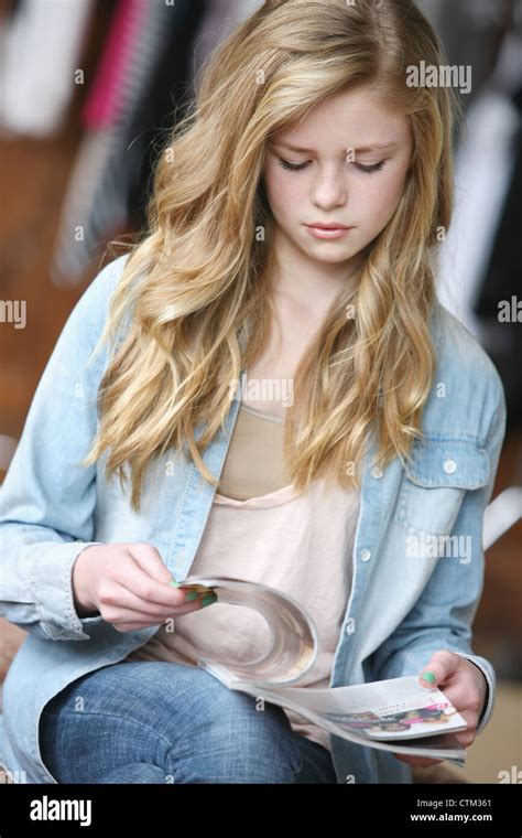 Teenage Girl With Long Blond Hair And Blue Eyes Reading A Magazine