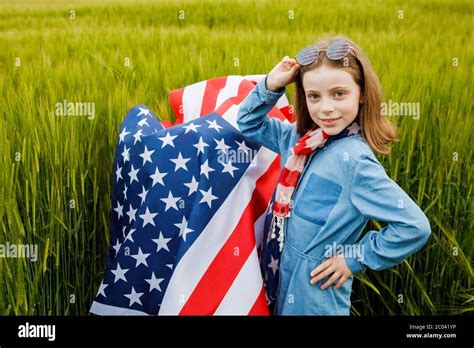 Pretty Young Pre Teen Girl In Field Holding American Flag Stock Photo