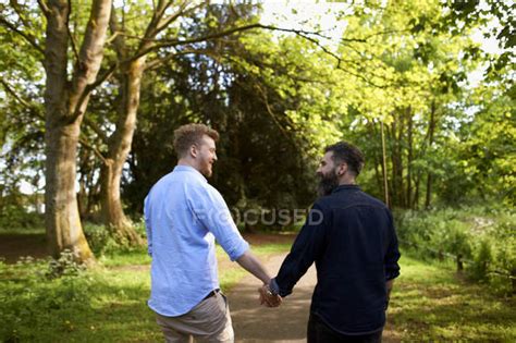 Affectionate Male Gay Couple Holding Hands In Sunny Park — Weekend Activities Gay Men Stock