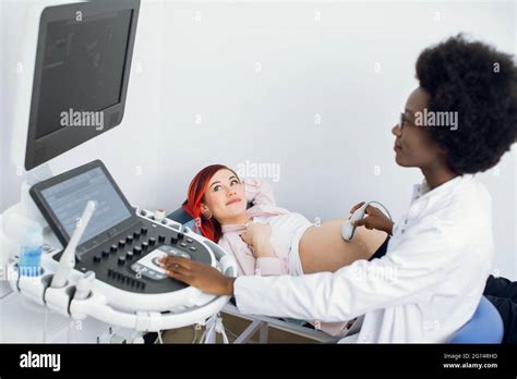 Young Pretty Pregnant Woman Getting Ultrasound Scan From Doctor Professional Confident African