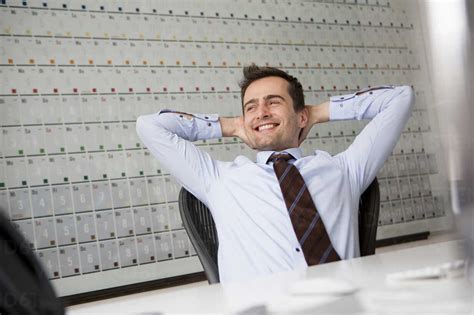 Businessman Leaning Back In Chair With Arms Behind Head Stock Photo