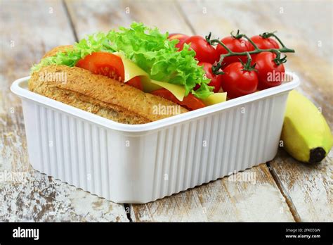 Healthy School Lunch Box Containing Whole Grain Cheese Sandwich Cherry Tomatoes And Banana