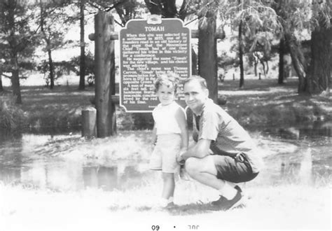 an old black and white photo of two people in front of a sign with names