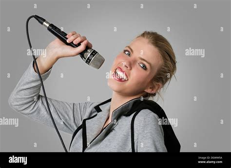 Young Woman Holding A Microphone In A Singer Pose Stock Photo Alamy