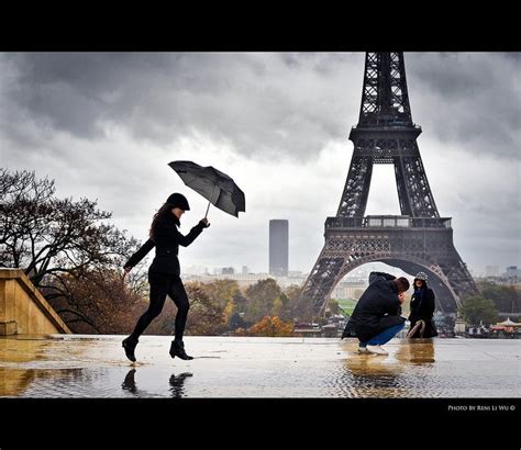 A Woman Holding An Umbrella In Front Of The Eiffel Tower