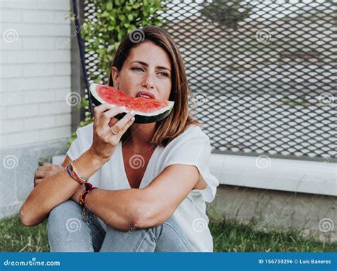 Caucasian Woman Eating Watermelon Slices In The Garden Of Her House And