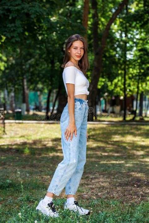 Young Beautiful Girl In Blue Jeans Posing In A Summer Park Stock Image