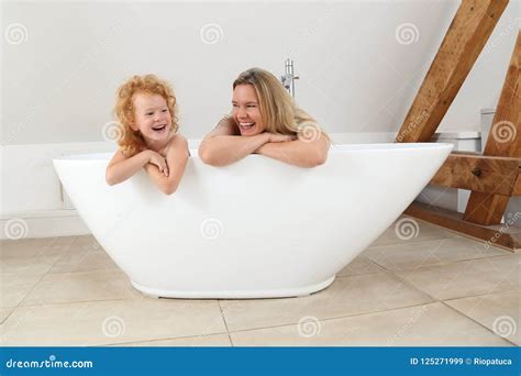 Mother And Daughter Looking Over The Edge Of A Freestanding Bath Tub