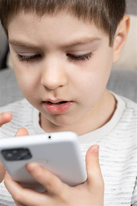 A Preschool Boy Uses A Smartphone Plays Games On His Phone Screen