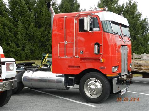 A Red Semi Truck Parked In A Parking Lot Next To Another White Truck