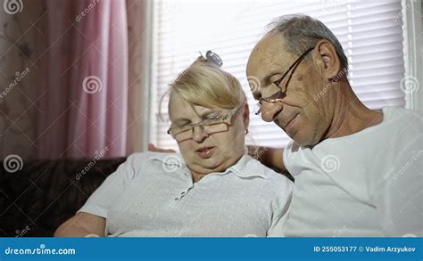 an adult couple looks at their photos sitting at home on the couch husband and wife with