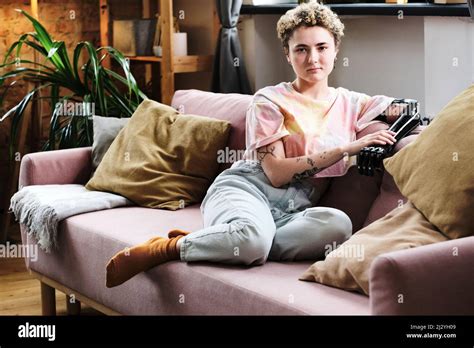 Portrait Of Young Woman With Prosthetic Arm Sitting On Sofa In Living