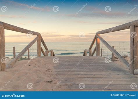 Wooden Staircase And Railing Access To The Beach Sand At Sunset Stock