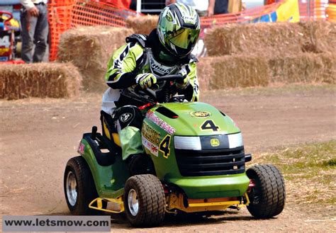 A Man Riding On The Back Of A Green Lawn Mower