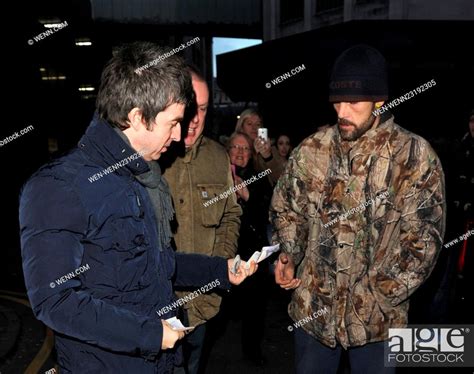 Noel Gallagher Hands A 20 Pound Note To A Homeless Man As He And His Wife Sarah Leave San Carlo